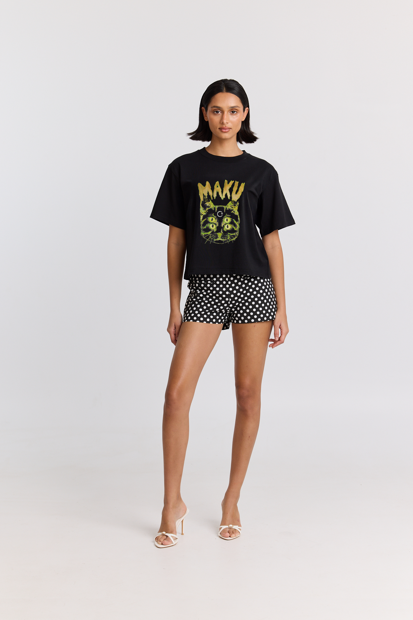 Woman wearing a black t-shirt with a CAT design and black polka dot shorts on a white background